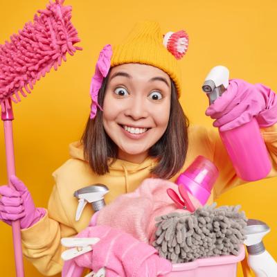 Smiling Glad Young Asian Woman Holds Spray Bottle Mop Stands Near Laundry Basket With Chemical Bottles Wears Rubber Gloves Uses House